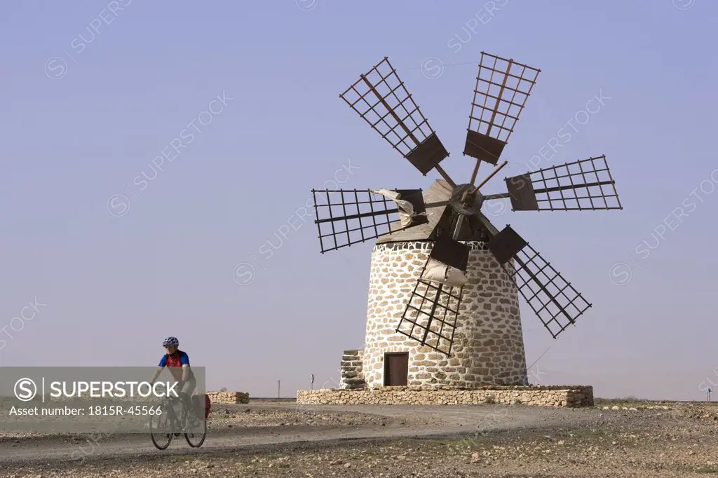 Spain, The Canary Islands, Man mountain biking, windmill in background