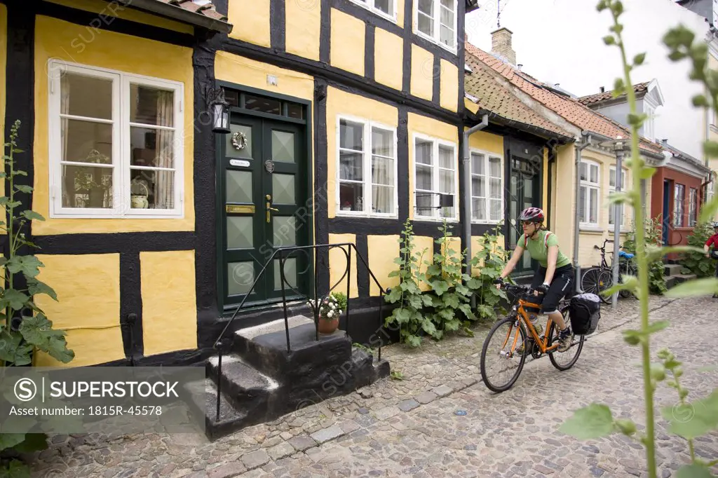 Denmark, Fuenen, Couple mountain biking alongside timbered houses