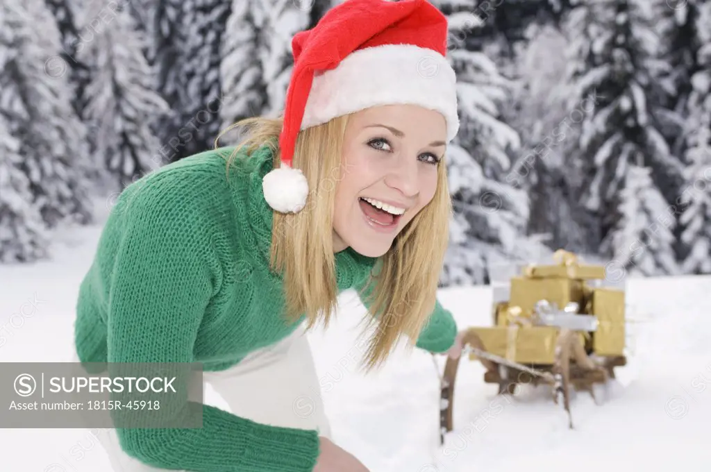 Austria, Salzburger Land, Altenmarkt, Young woman pulling slege with Christmas presents, close-up