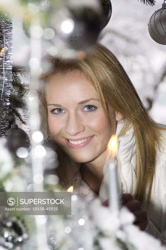 Austria, Salzburger Land, Young woman at Christmas tree, smiling, portrait, close-up
