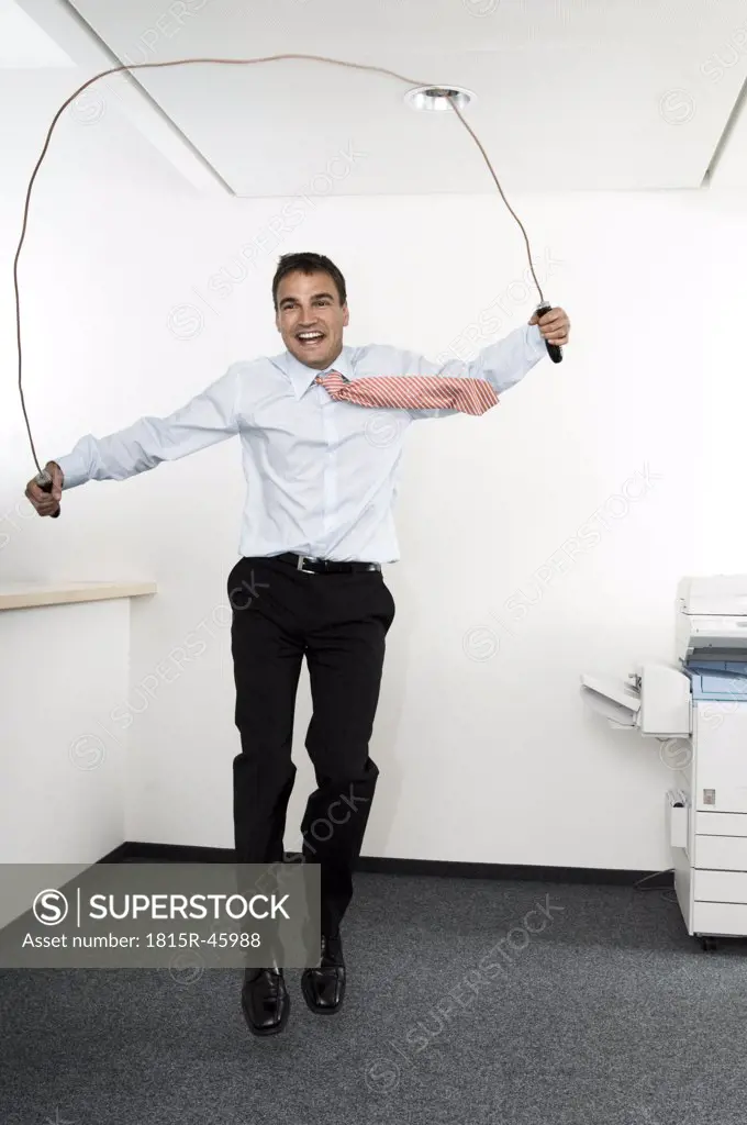 Businessman using skipping rope in office