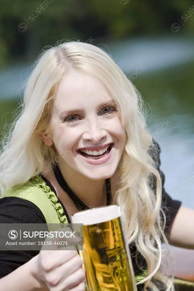 Germany, Bavaria, Munich, English Garden, Young woman holding beer stein, portrait, close-up