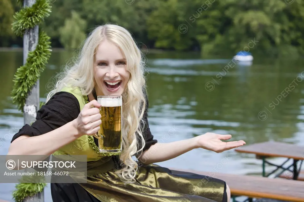 Germany, Bavaria, Munich, English Garden, Young woman holding beer stein