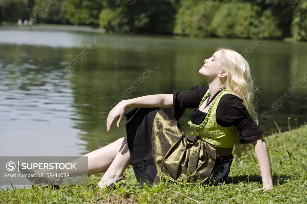 Germany, Bavaria, Munich, English Garden, Woman sitting on the lakefront