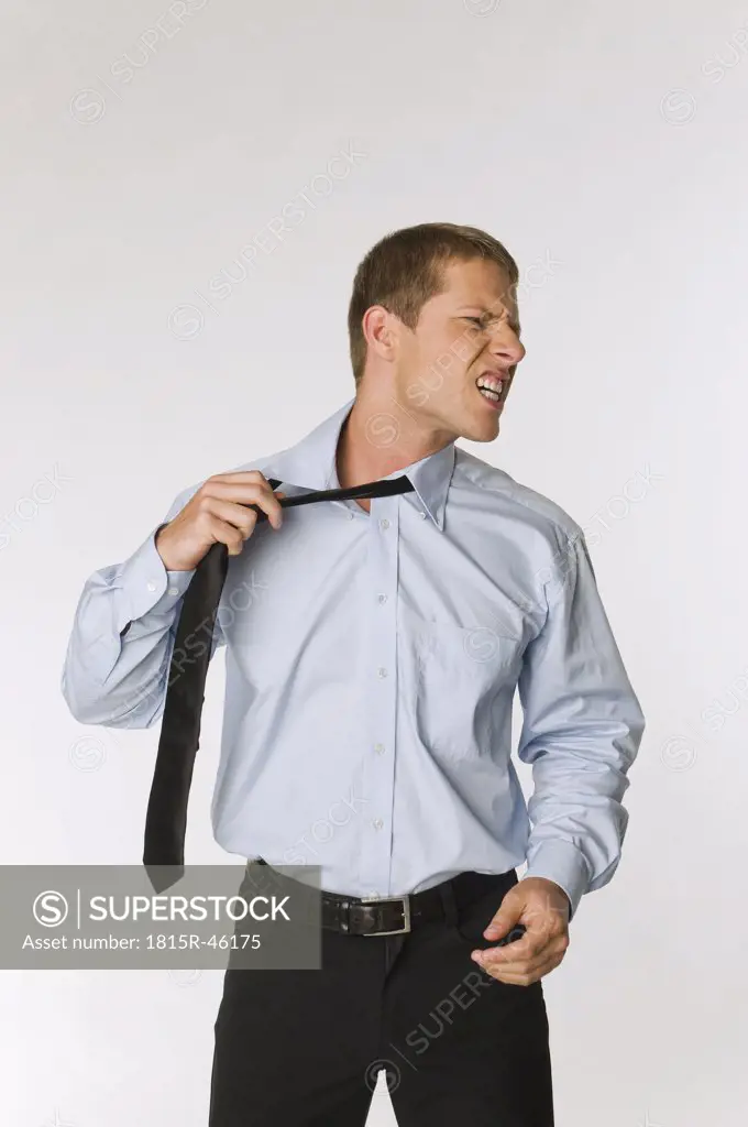 Businessman loosening his tie, looking angry
