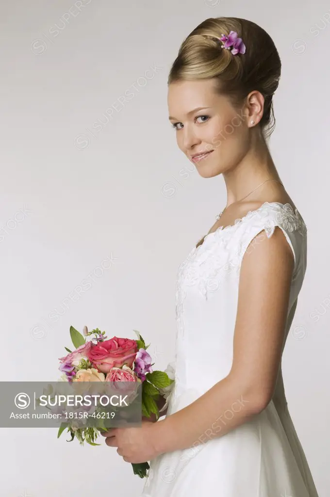 Young bride holding bridal bouquet, side view