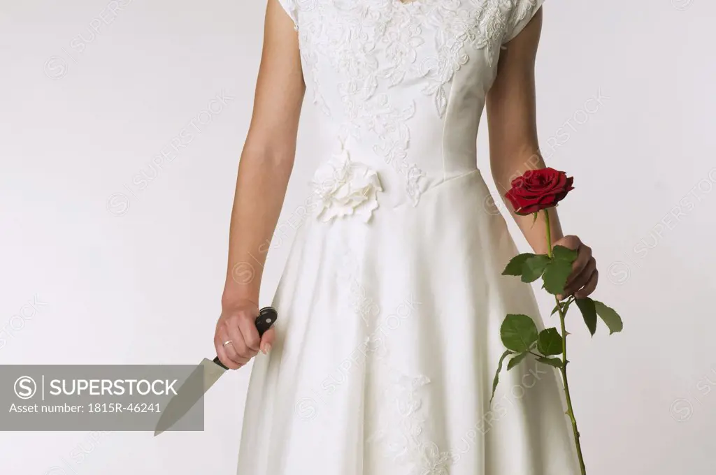 Bride holding a knife and a rose, mid section