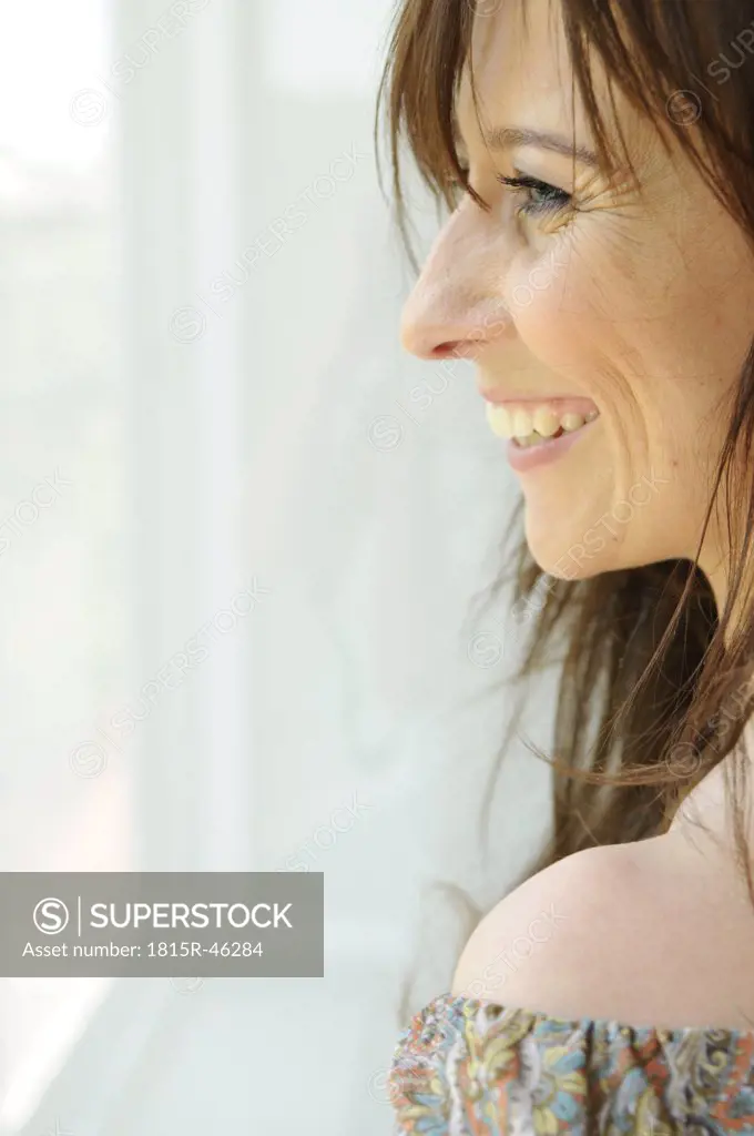 Young woman looking through window, portrait, close-up