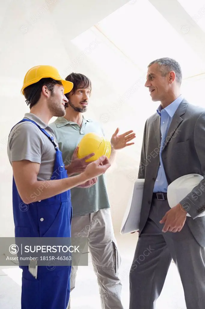 Two men talking to Architect at construction site