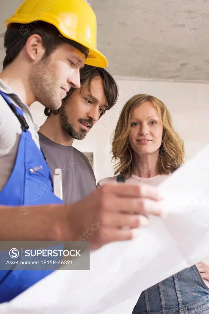 Young couple and construction worker looking at construction plan