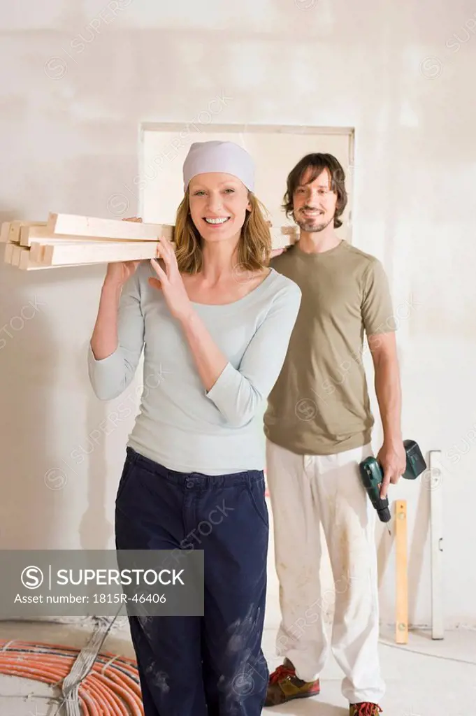 Young couple carrying wooden planks at home, portrait