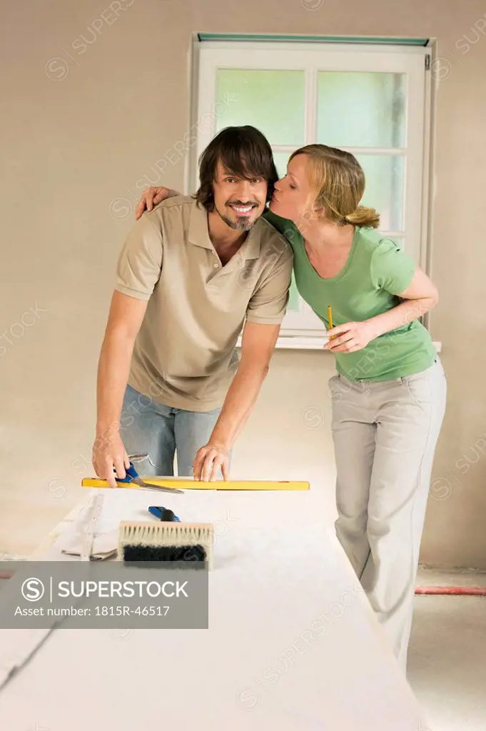 Young couple renovating, Woman kissing man