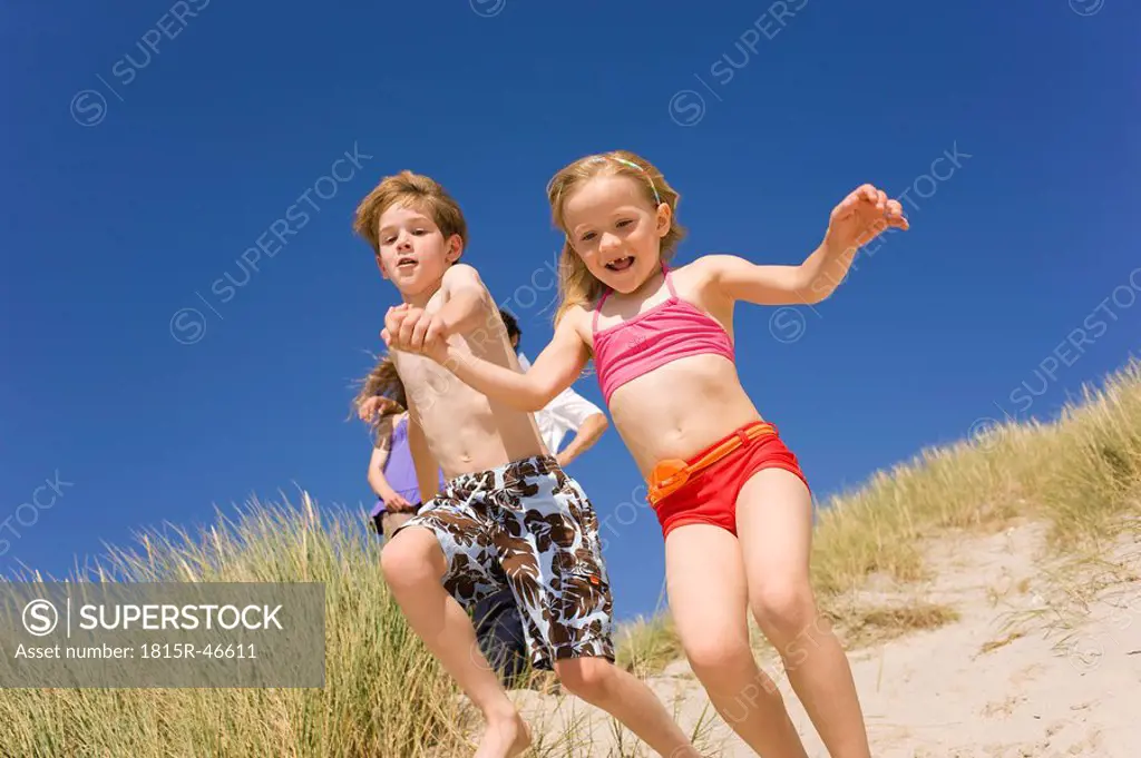 Germany, Baltic sea, Boy 8_9 and girl 6_7 jumping down beach dune