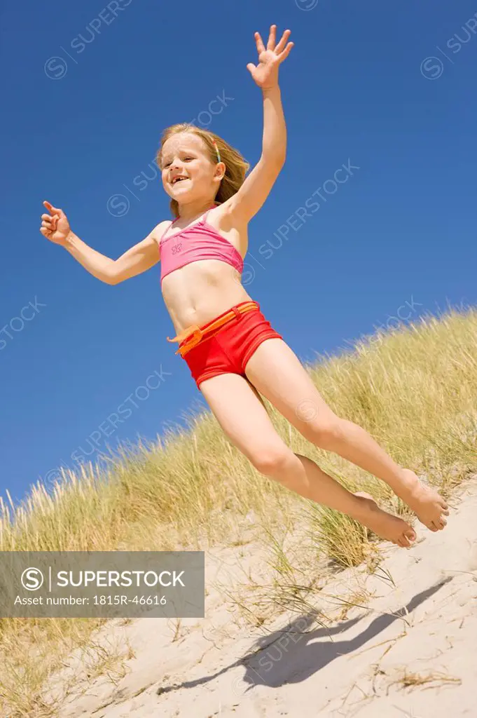 Germany, Baltic sea, Girl 6_7 jumping down sand dunes