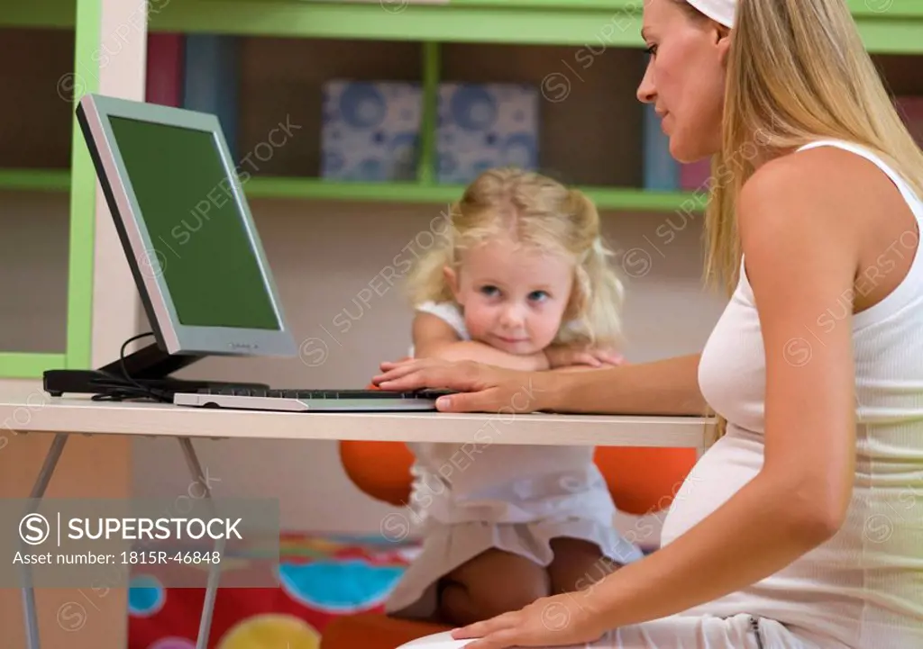 Pregnant mother and daughter 3_4, using computer