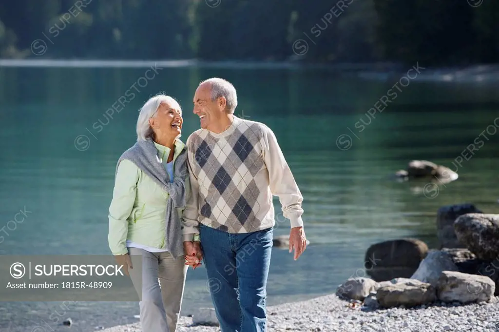 Germany, Bavaria, Walchensee, Senior couple walking across lakeshore