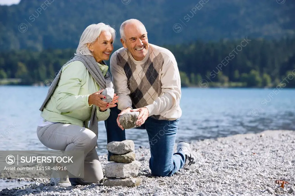 Germany, Bavaria, Walchensee, Senior couple piling up stones