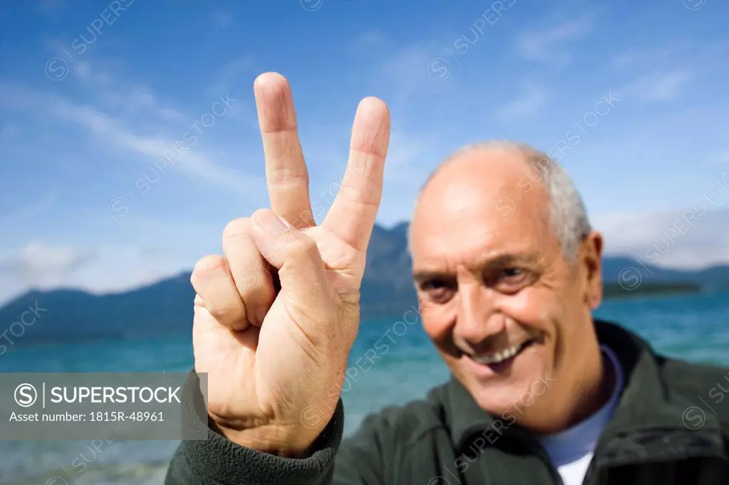 Germany, Bavaria, Walchensee, Senior man showing victory sign