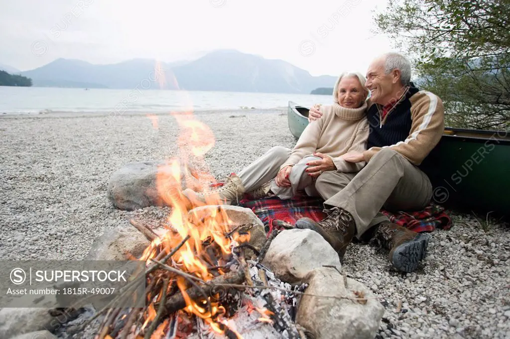 Germany, Bavaria, Walchensee, Senior couple sitting at campfire