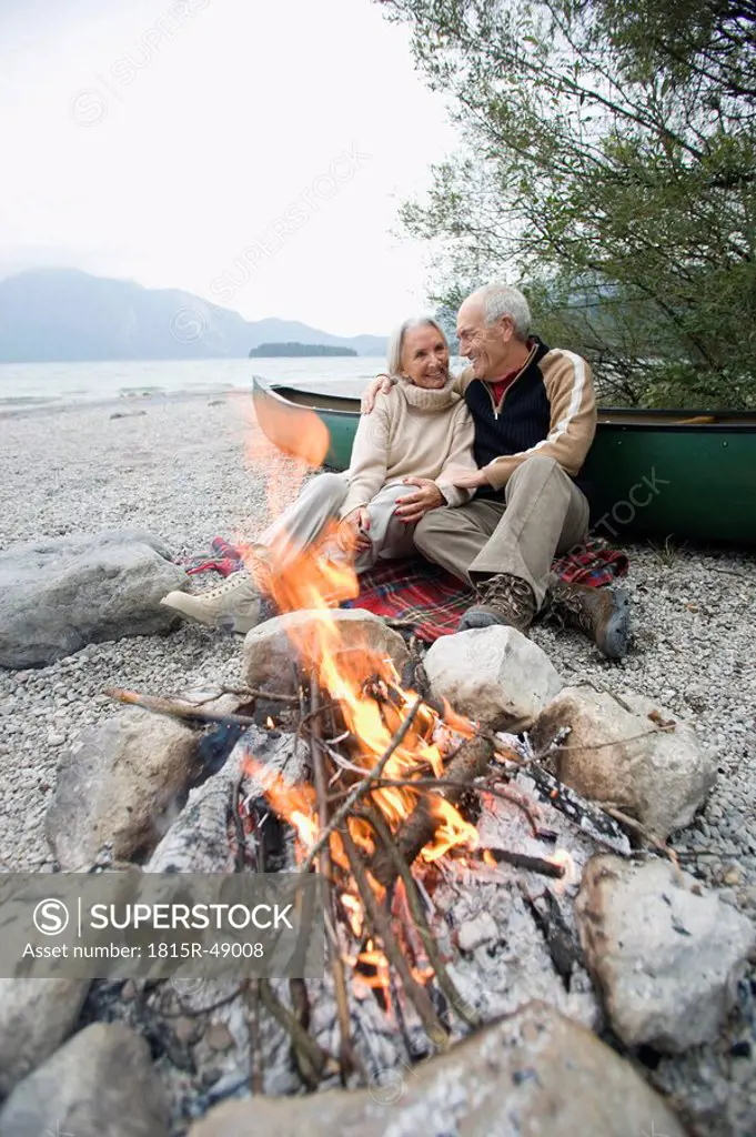 Germany, Bavaria, Walchensee, Senior couple sitting at campfire