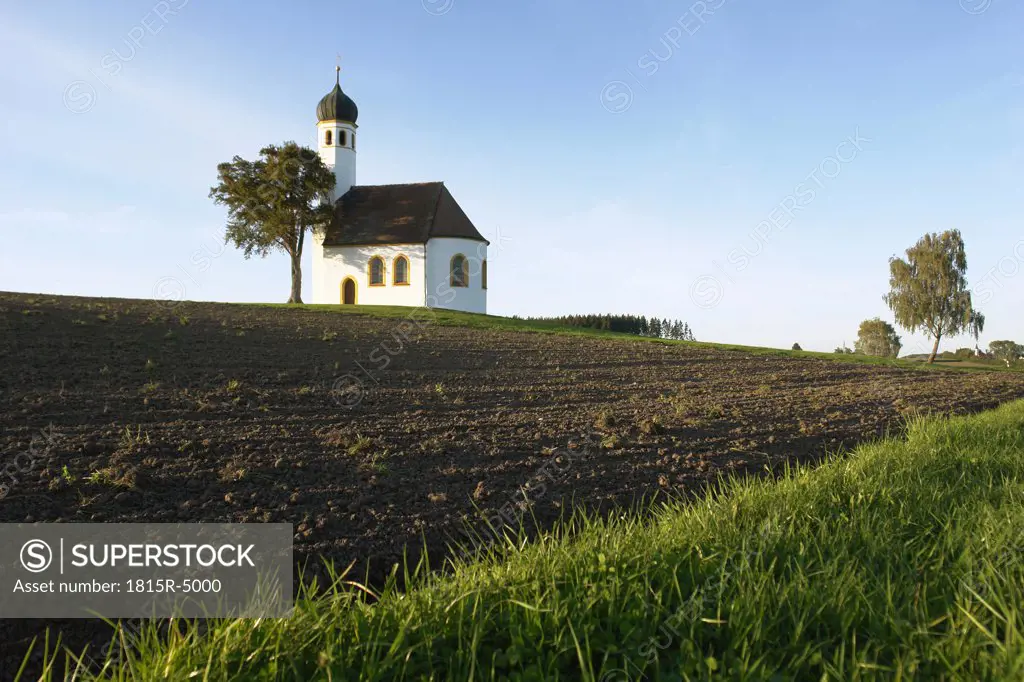 Germany, Bavaria, chapel with onion spire on a bank and fields
