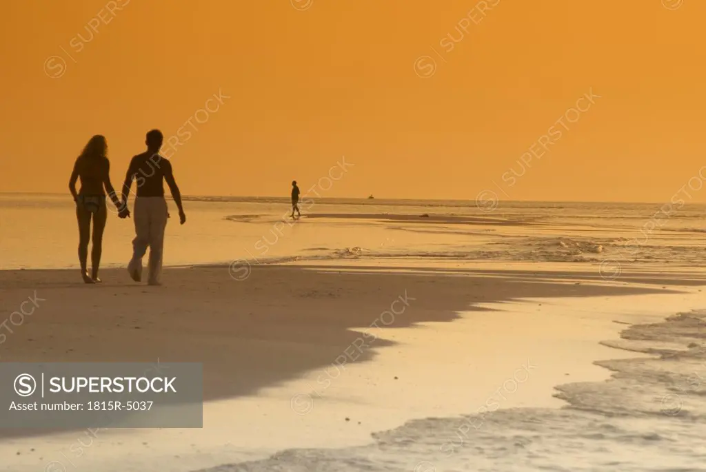 Couple on the beach, silhouetted at sunset, Maldives