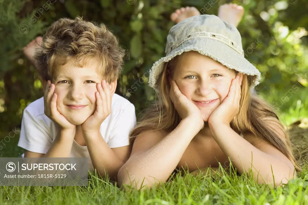 Boy and girl (6-9) lying on grass, portrait