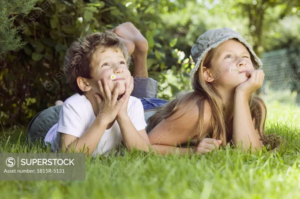 Boy and girl (6-9) lying on grass, looking up