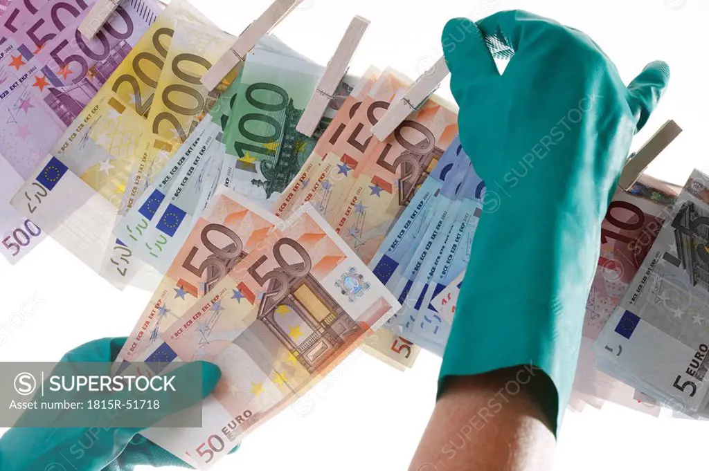 Person hanging different Euro notes on clothesline, close_up