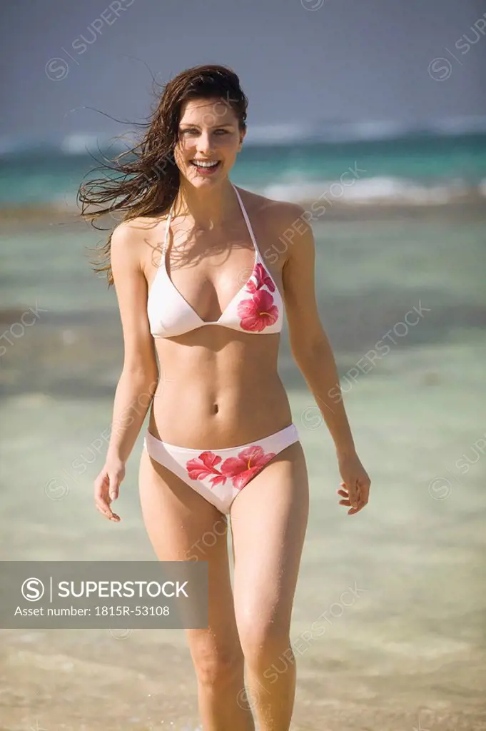 Young woman on beach, smiling, portrait