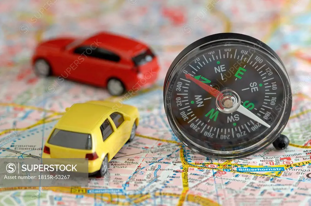 Toy cars and compass on city map, close up
