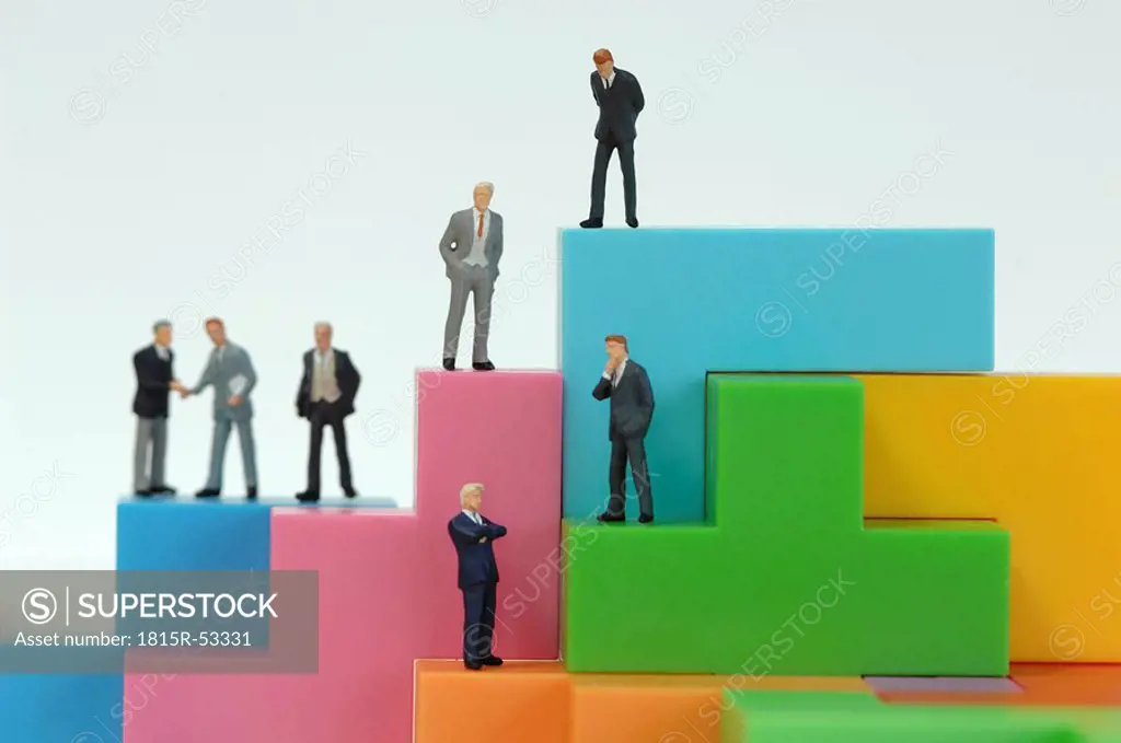 Businessman figurines on bright building bricks, close up