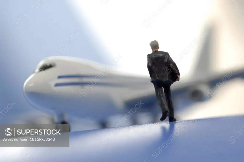 Business man figurine in front of airplane