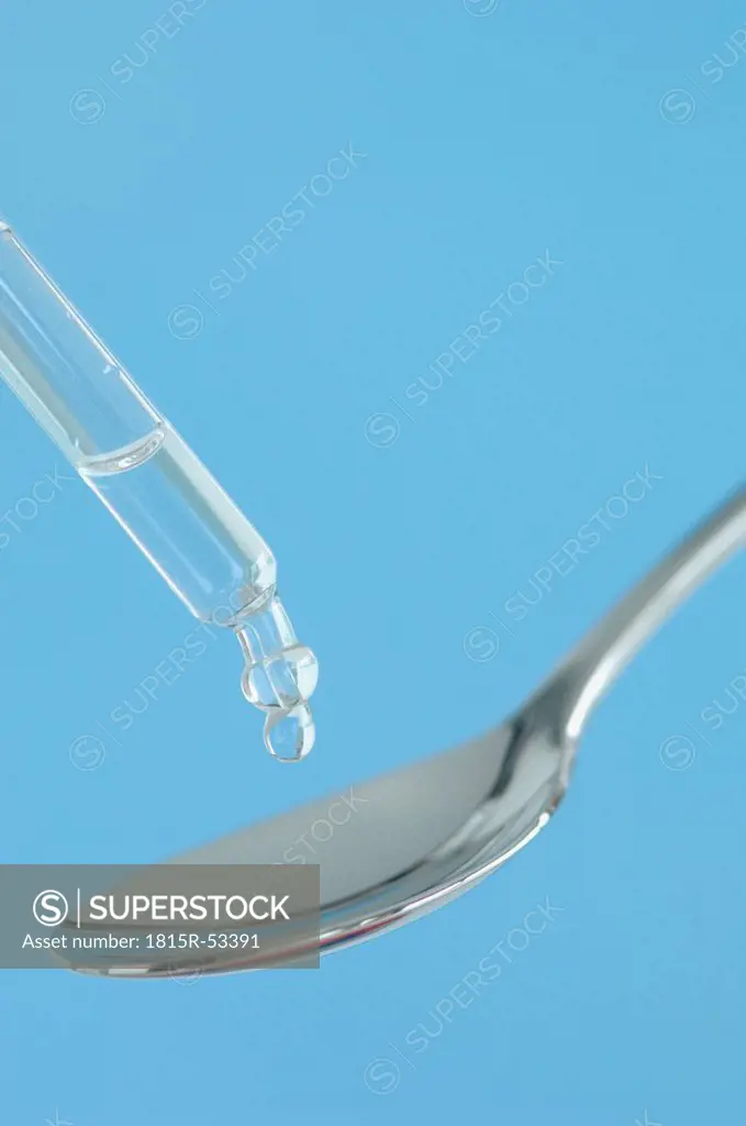 Drop falling from a pipette onto spoon, close_up
