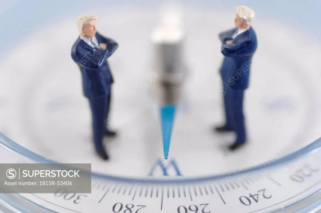 Businessman figurines placed on compass, close up
