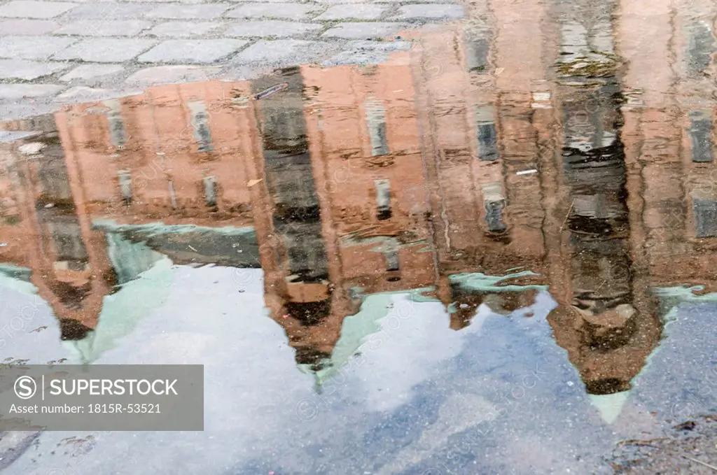 Germany, Hamburg, Old warehouse district, buildings reflected in puddle on road