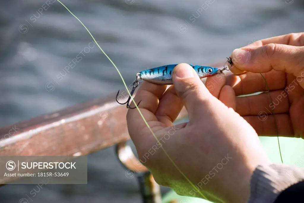 Man´s hand fixing bait on hook, elevated view