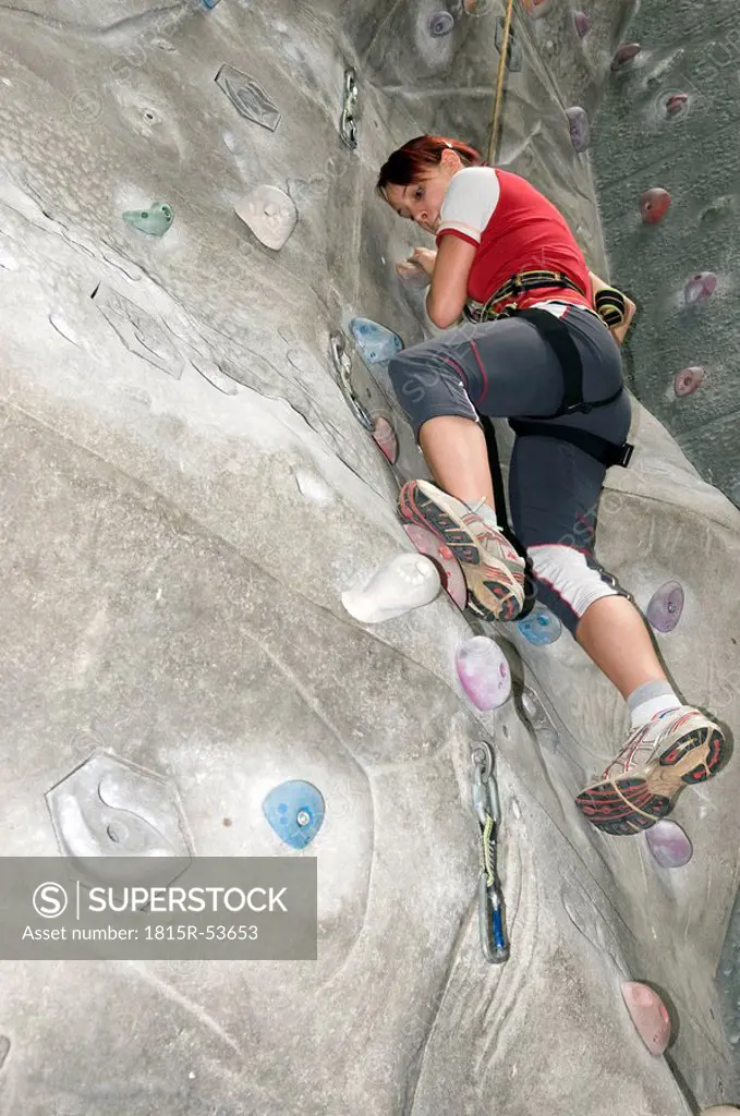 Young woman on indoor climbing wall, low angle view