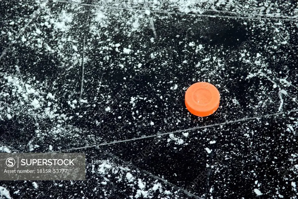 Ice hockey puck on frozen water surface, elevated view