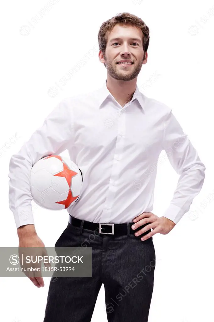 Young man holding soccer ball, smiling, portrait