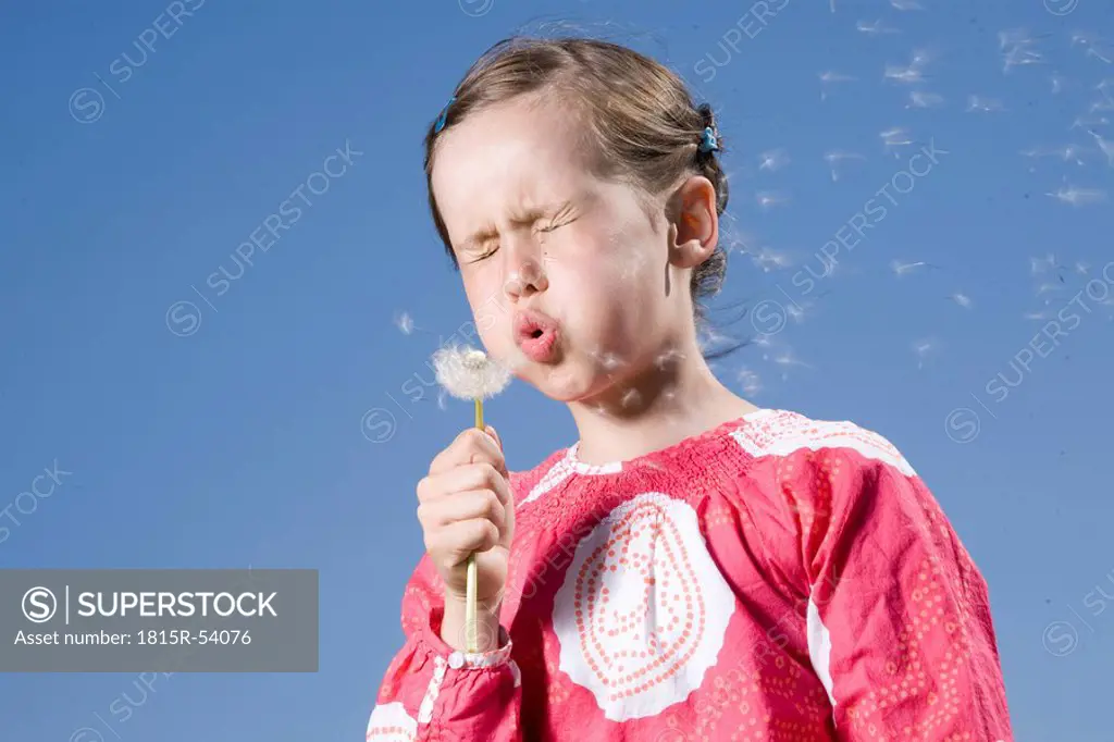 Young girl 6_7 blowing a dandelion