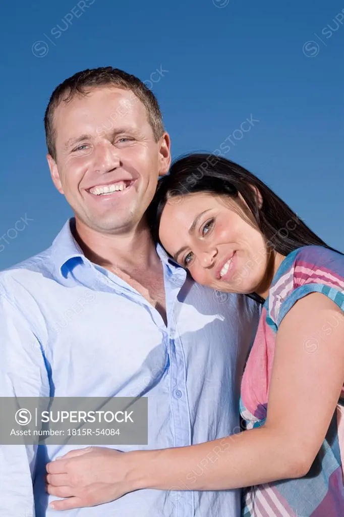 Young couple embracing, smiling, portrait