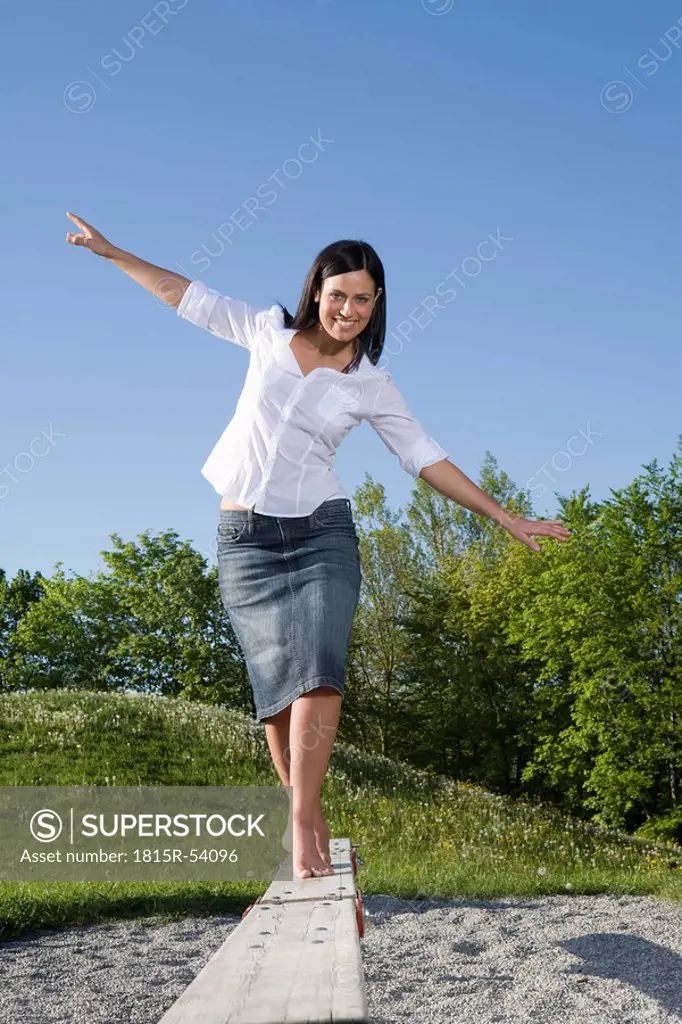 Young woman balancing on boardwalk in a playground