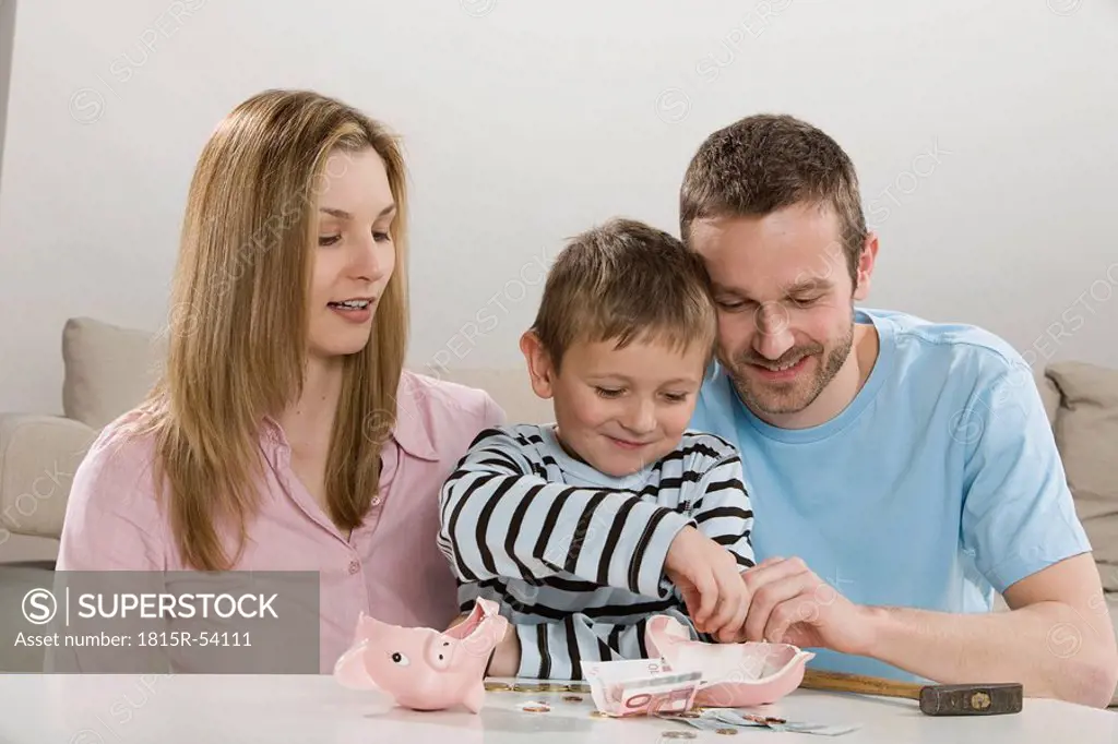 Parents and son 4_5 looking at broken piggybank, counting money