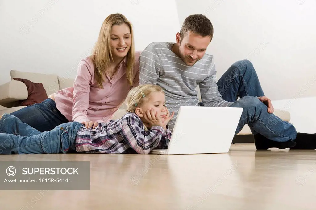 Parents and daughter 3_4 at home, using laptop