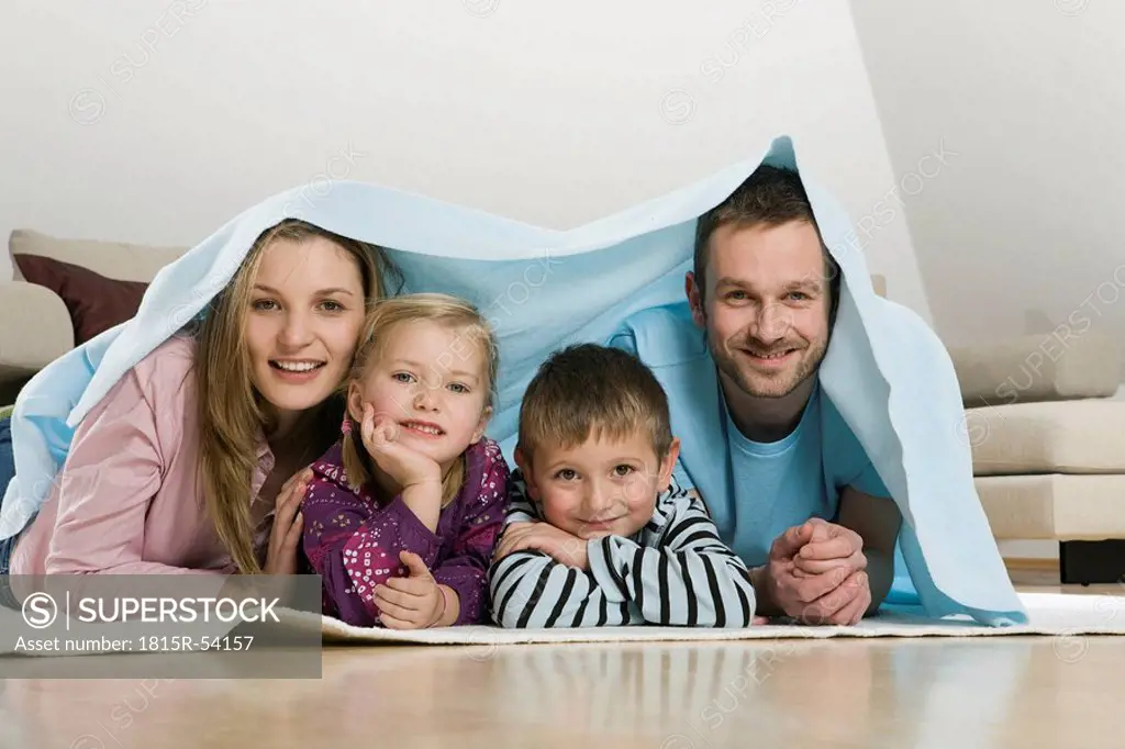 Family covered with blanket, smiling