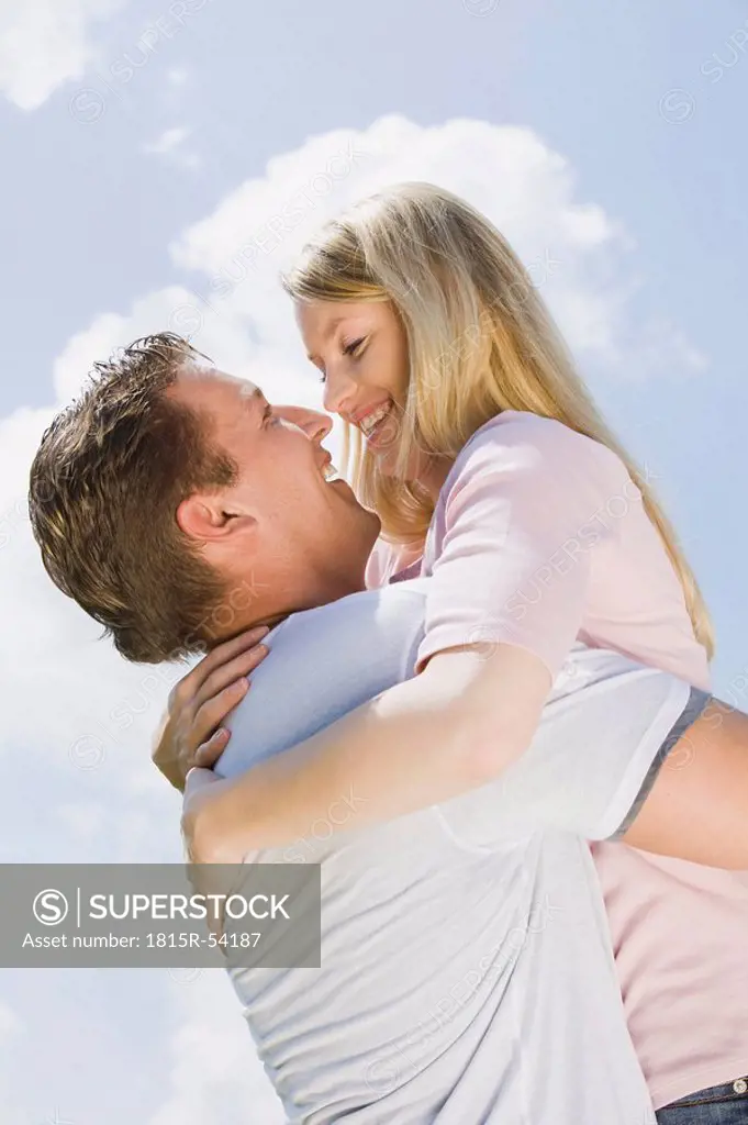 Germany, Bavaria, Munich, Young couple, man lifting woman, side view, portrait