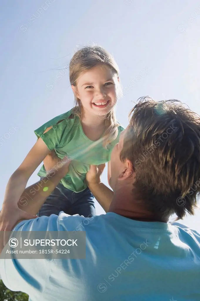 Germany, Bavaria, Munich, Father lifting daughter 6_7, smiling, portrait