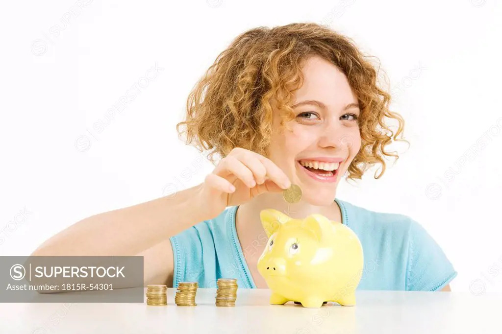 Young woman with Euro coins and piggy bank, smiling, portrait