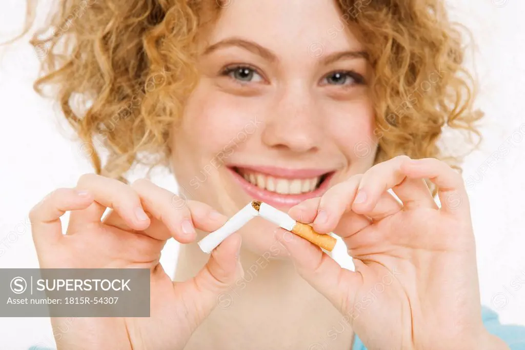 Young Woman breaking cigarette in half, smiling, portrait